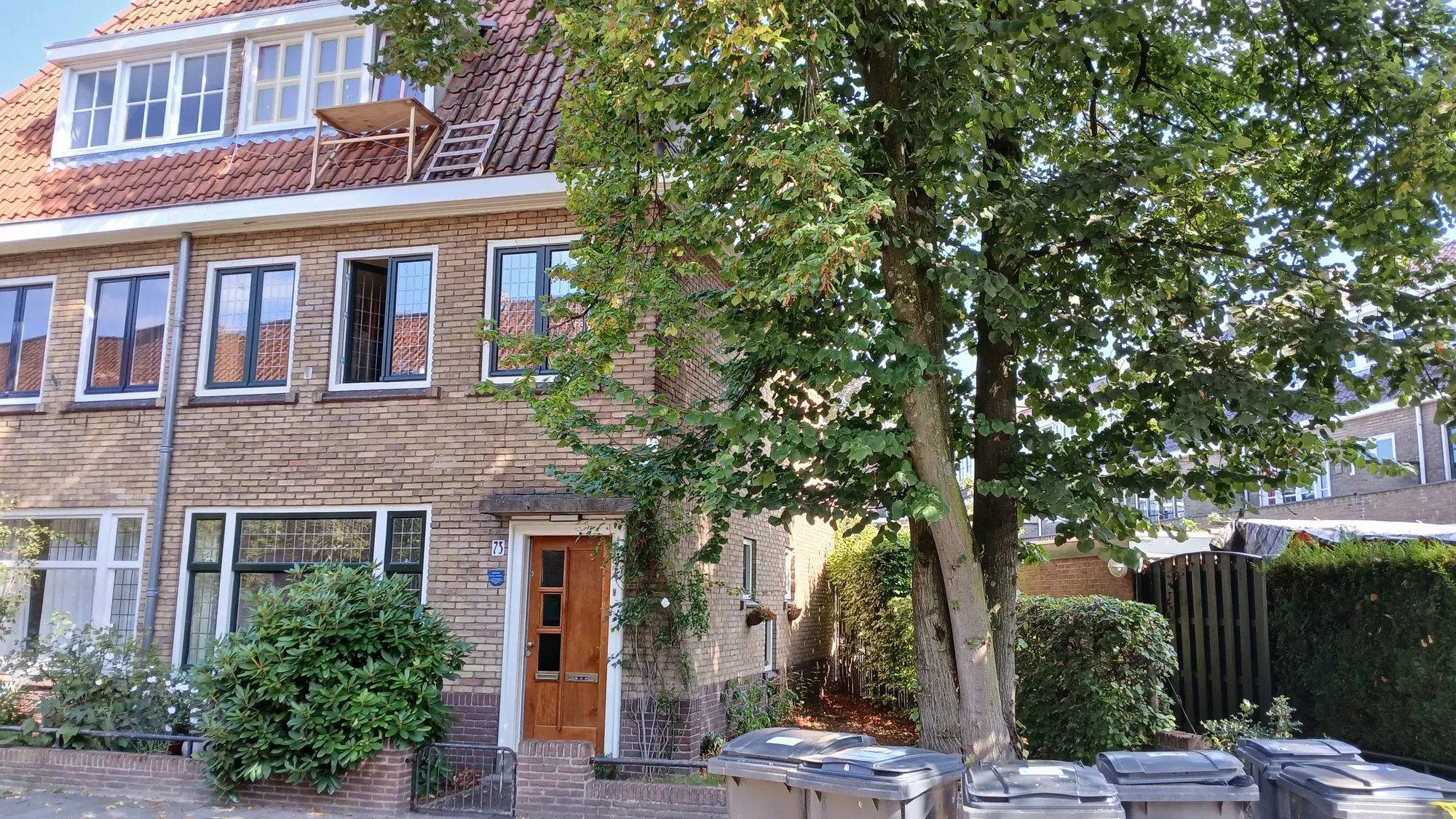 Het huis in 2024, met rechts een uitgegroeide boom die het dak voorbij reikt